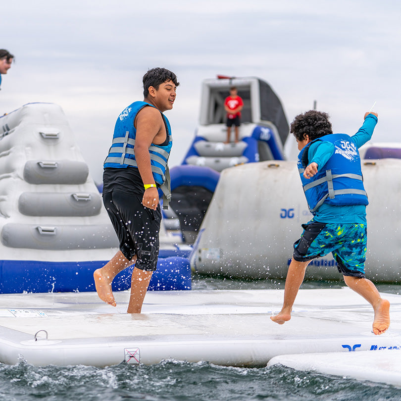 Two kids in life jackets play on a Landing Pad.